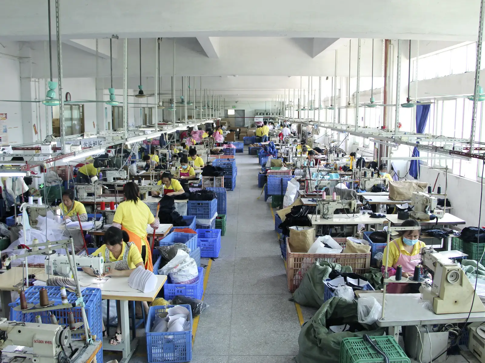 Rows of sewing stations and fabric components in a cap production workshop.