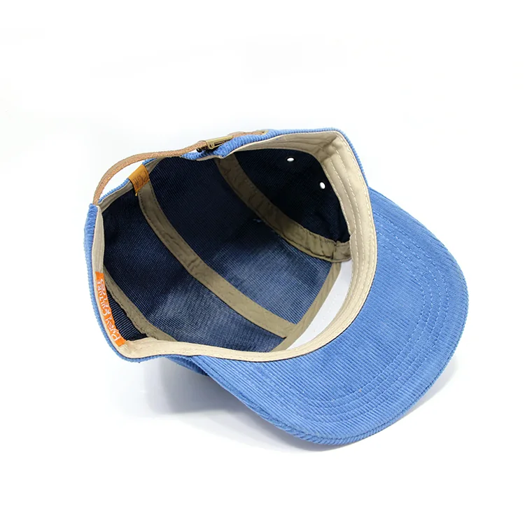Interior of the blue corduroy camp cap showing light-colored seam binding, a sweatband and the brown rear strap.