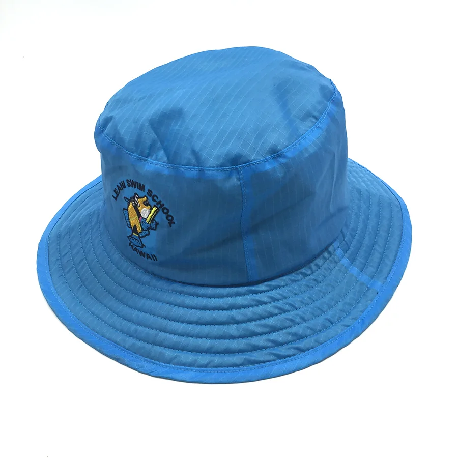 Oblique view of the blue bucket hat with the fish embroidery visible to one side and concentric brim stitching.